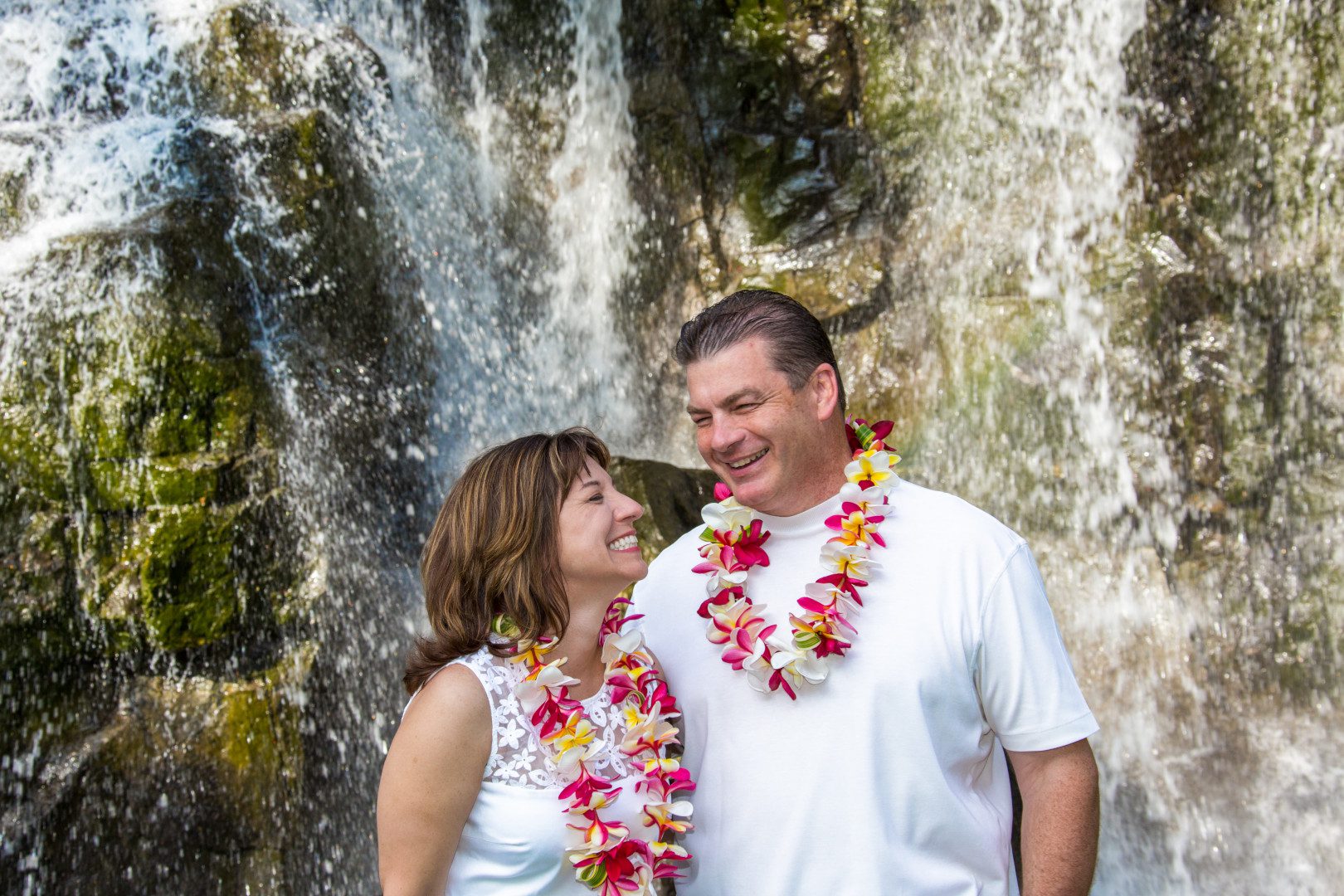 A happy couple near waterfall posing for wedding picture