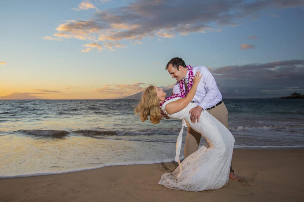 A couple dances on the beach at sunset.