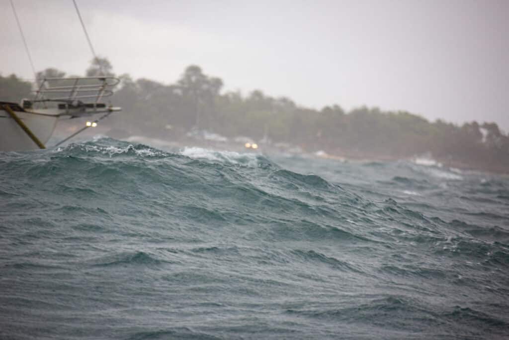 A stormy sea with large waves and a distant ship.