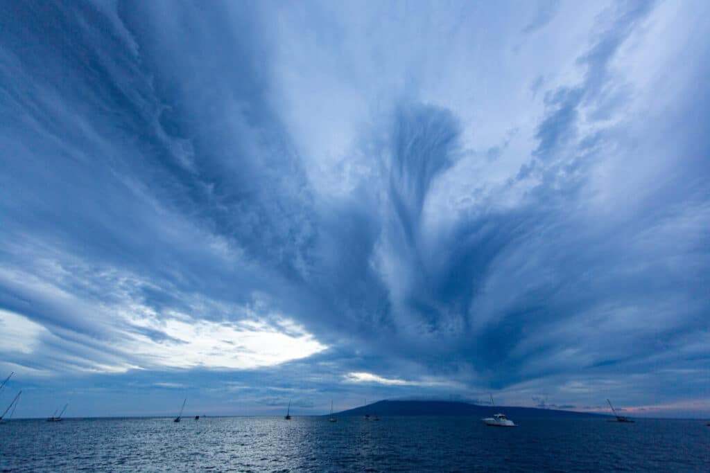 blue clouds at night with sailboats and boats around.