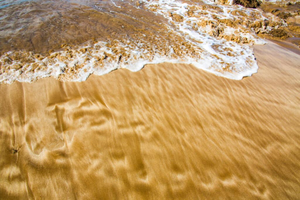 Ocean waves gently washing over golden sandy beach.