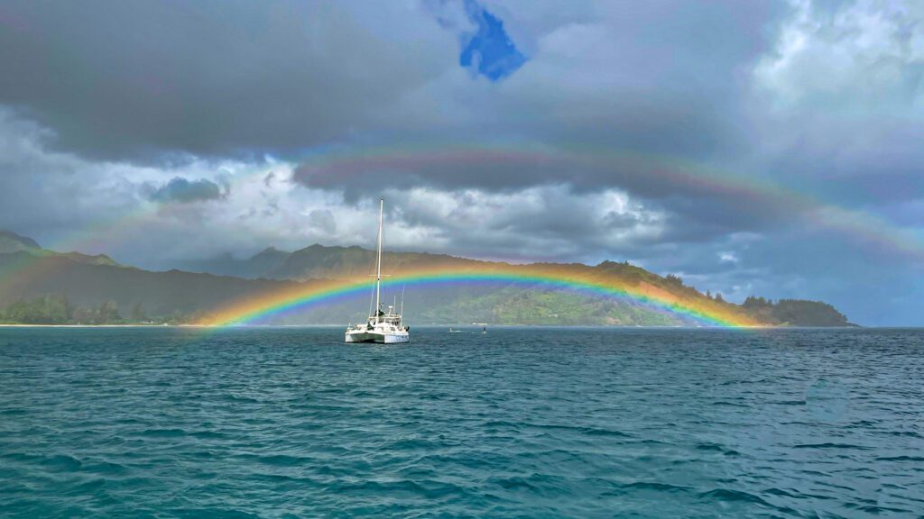 Our sailboat Chat d'O anchored in Hanalei Bay Kauai under a rainbow. 