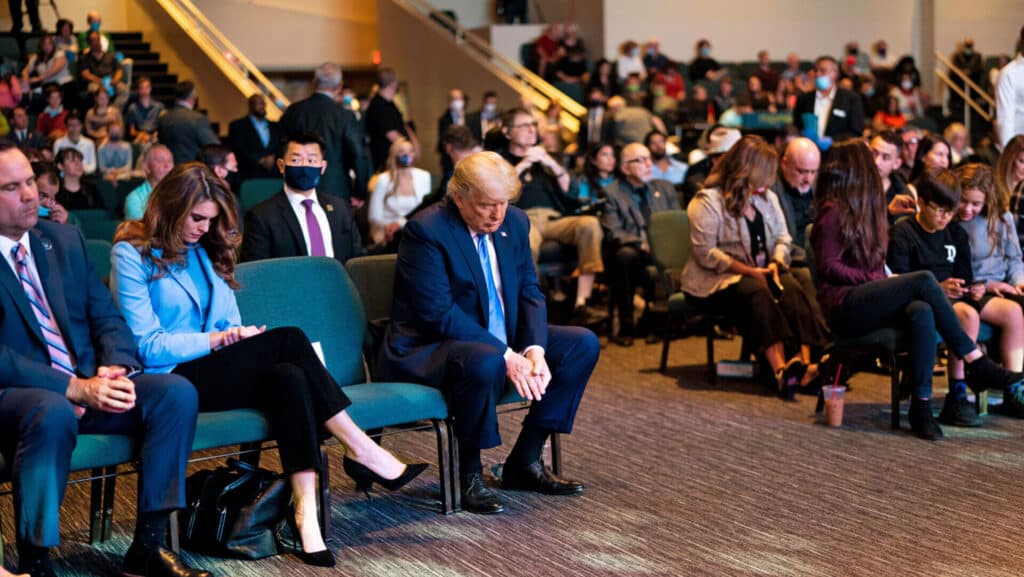 People seated indoors, attentively listening.