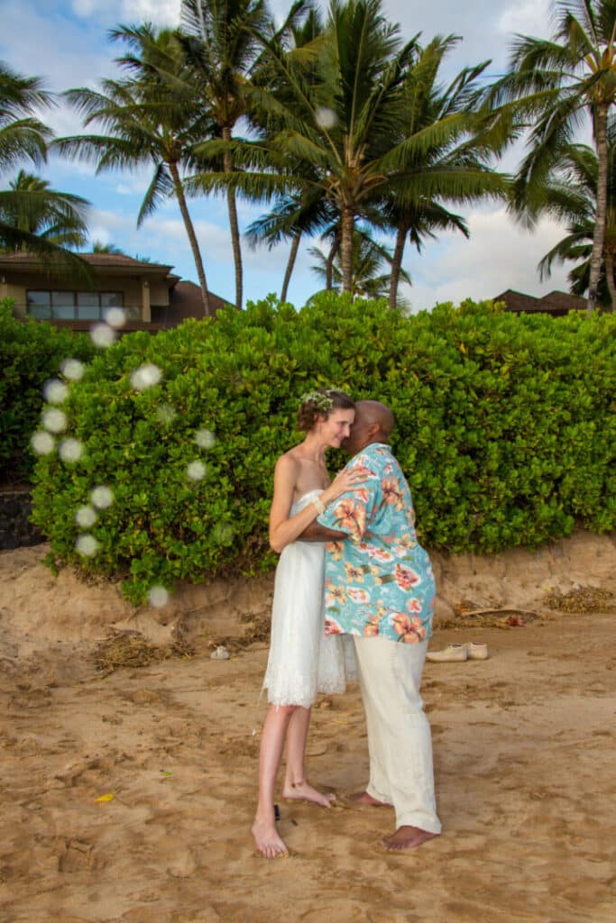 Couple sharing a kiss on a tropical beach with palm trees.