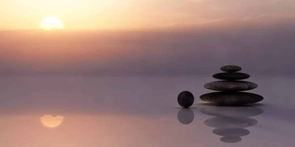 Balanced stones on a reflective surface at sunset.