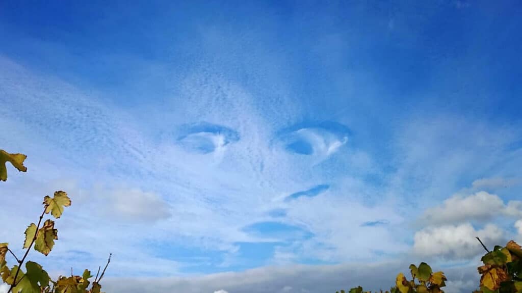 A face formed by clouds in a blue sky.