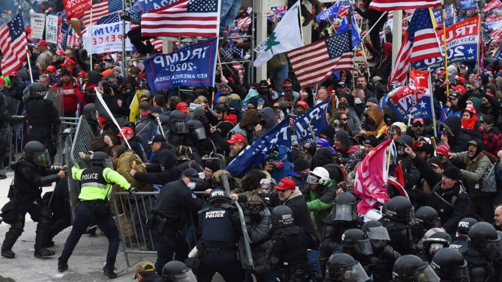 A crowd holding American flags and Trump 2020 banners at a rally.