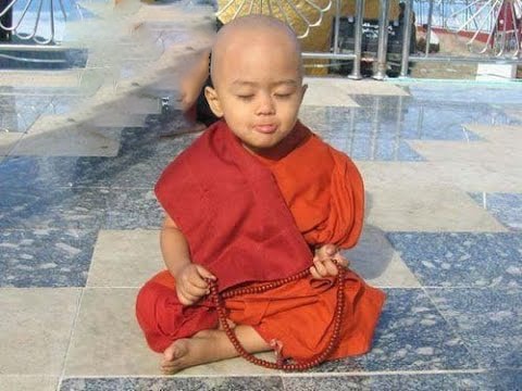 Young child meditating with prayer beads.