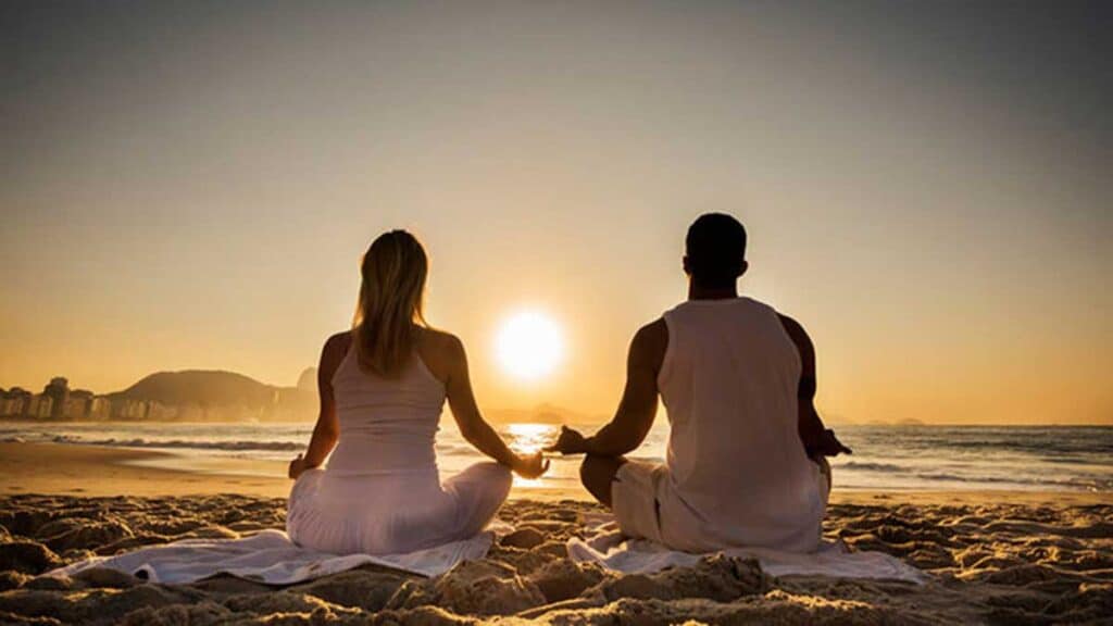 Spiritual Meditation. Couple sitting on the beach meditating