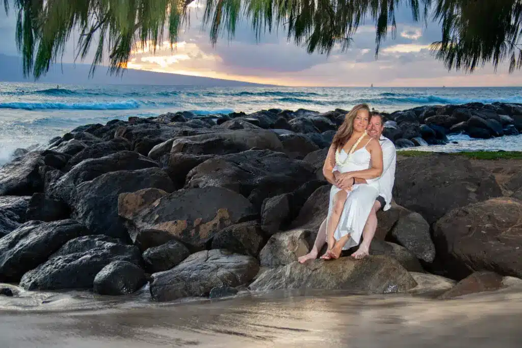 couple posing on a wall of rocks at a beach in Maui before the wedding