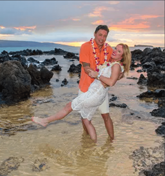 Couple taking a photo with the beach in the background in Maui HI