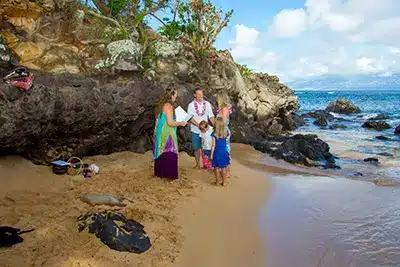 Young kids next to mom and dad as they get married on a beach in Maui