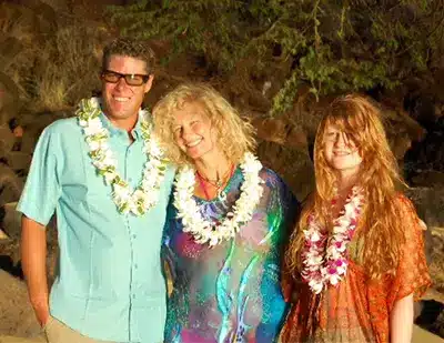 Mom, Dad, and daughter taking a photo on a beach in Maui.