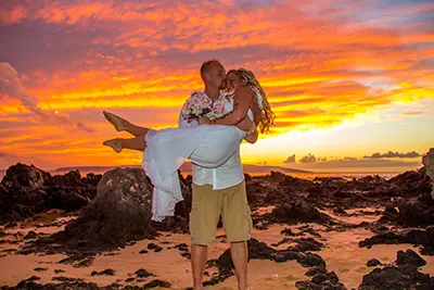 Groom carrying wife for a sunset photo in Maui after their wedding