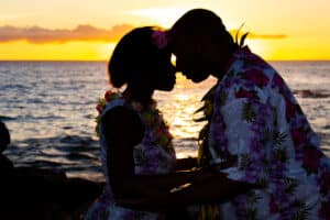 Silhouetted couple sharing a tender moment at sunset by the ocean.